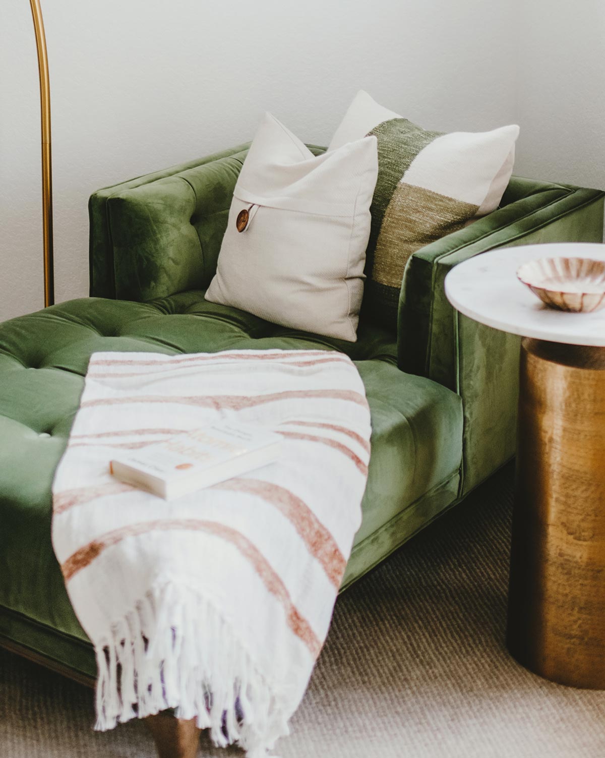 A tasteful green chair with a stylish blanket